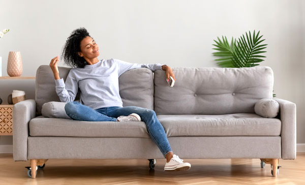 A woman lounges on her sofa, stress-free and delighted to maintain the cleanliness of her home.