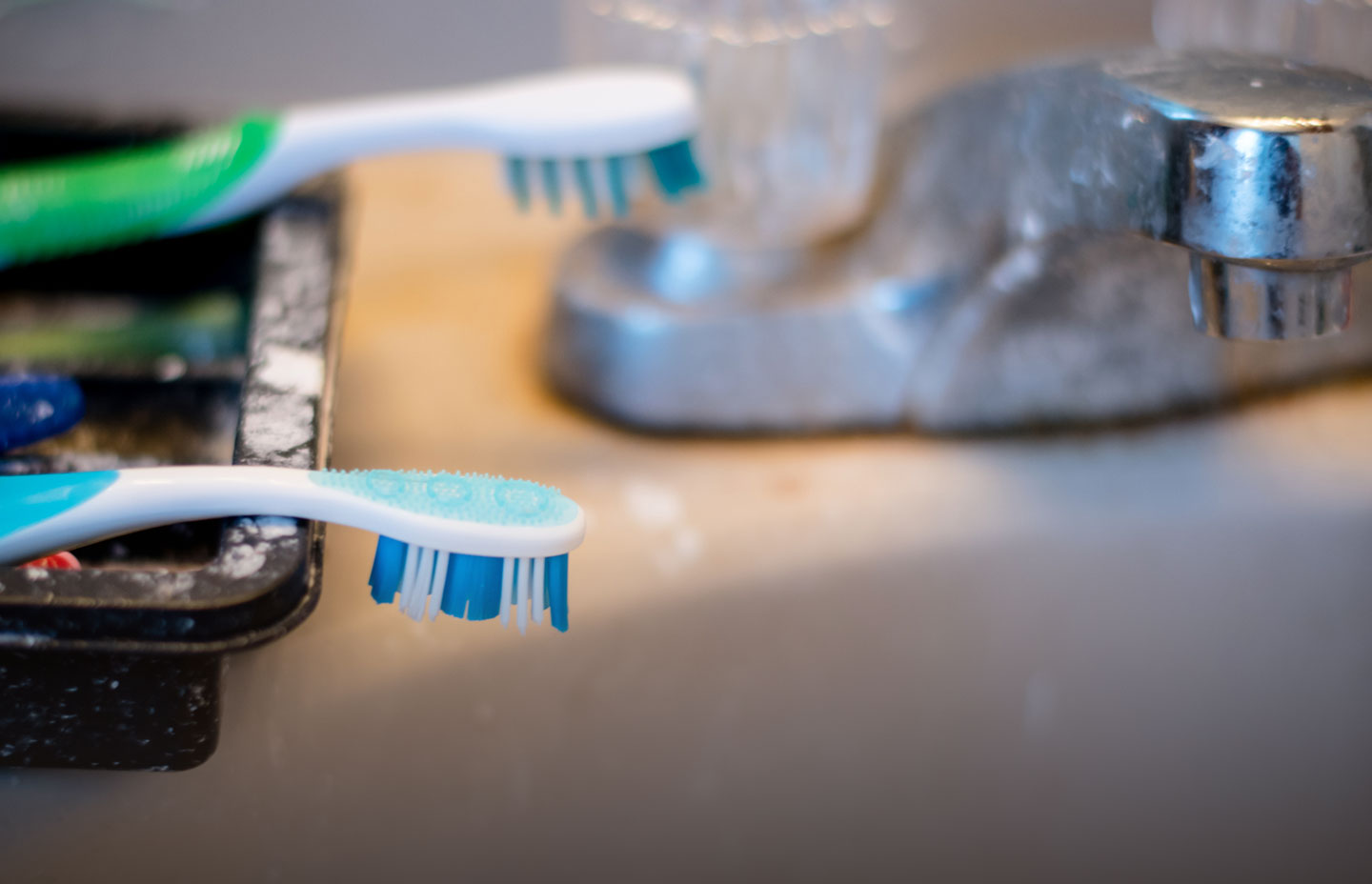 A couple of toothbrushes employed for cleaning bathroom faucets.