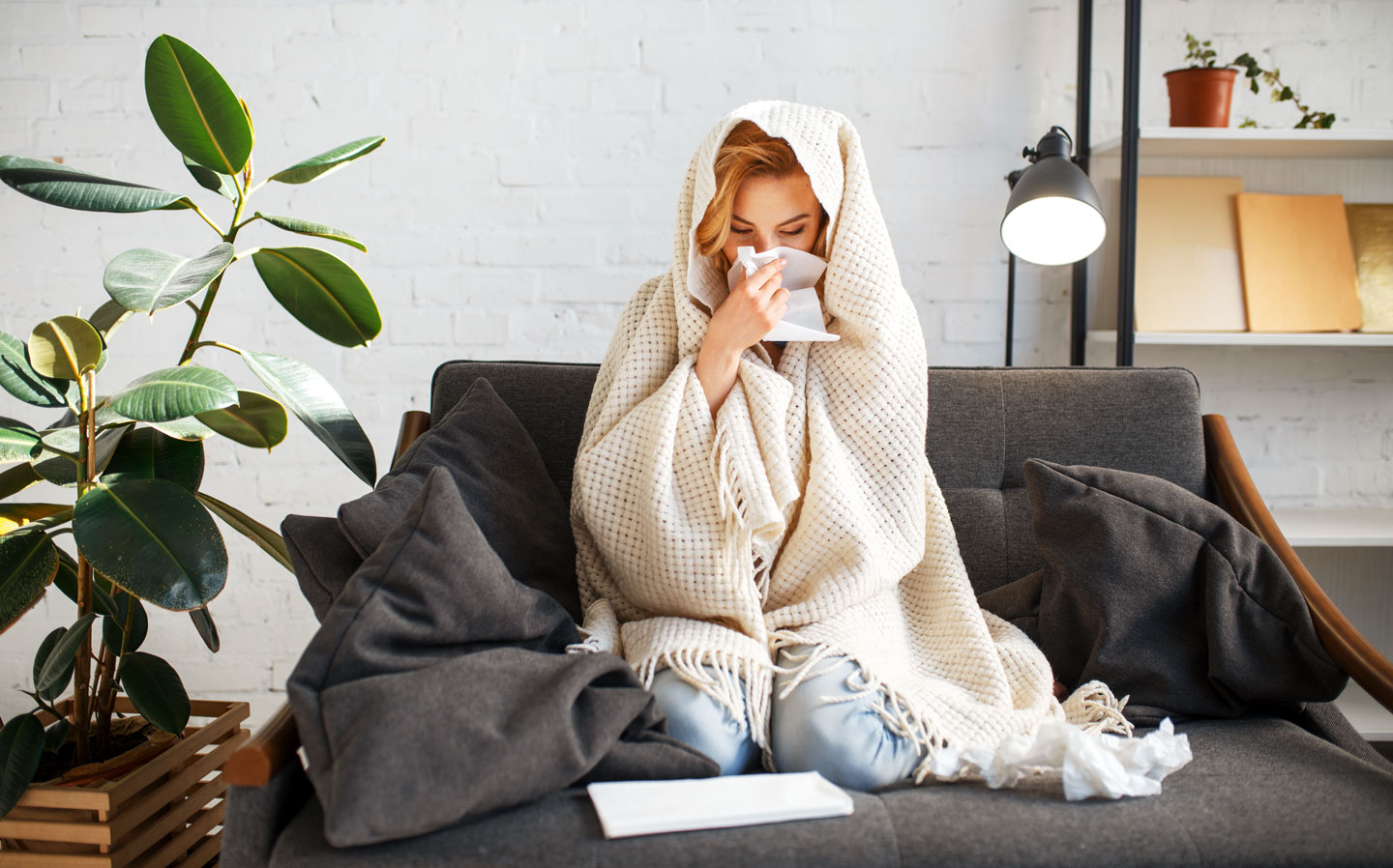 Woman experiencing the symptoms of a flu sitting in a sofa